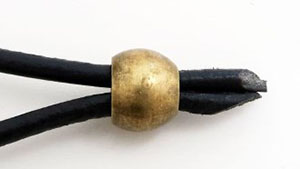 両端の穴の大きさが違う、紐を締めるメタルビーズに適合する革紐の例